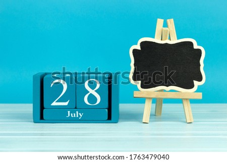 wooden calendar with the date of July 28 and an easel on a blue background, place for text, World Hepatitis Day