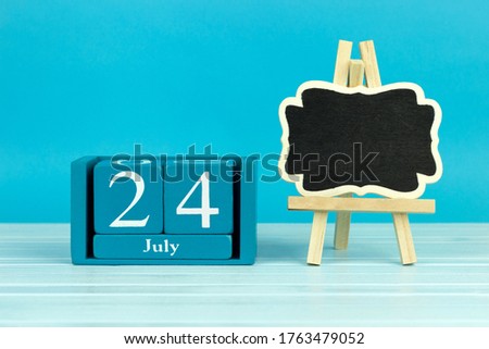 wooden calendar with the date of July 24 and an easel on a blue background, place for text, 
International day of self-care