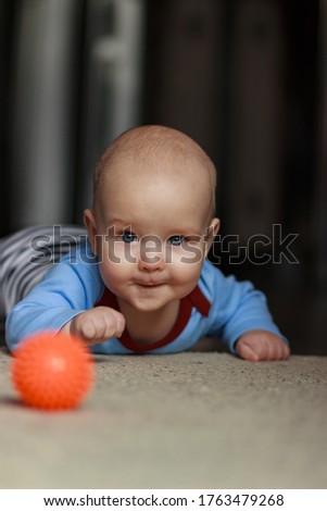 little boy crawls on all fours on the floor of the house with a serious look like an adult