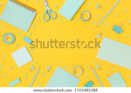 Border frame made of mint color school equipment on a bright yellow background. Creative concept with place for text.
