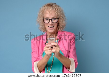 Happy mature lady hold cellphone texting or messaging, smiling senior woman use smartphone send sms type email.