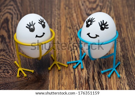 two funny smiling eggs on stands, on a wooden table, close-up