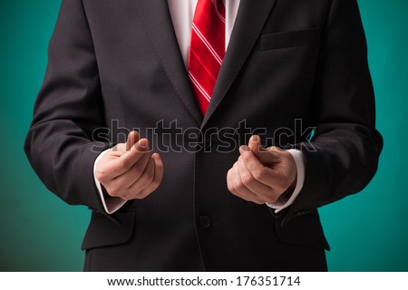 Businessman asking for money in black suit and red tie on green background.