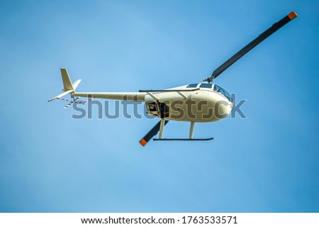 White helicopter flies in blue cloudless sky