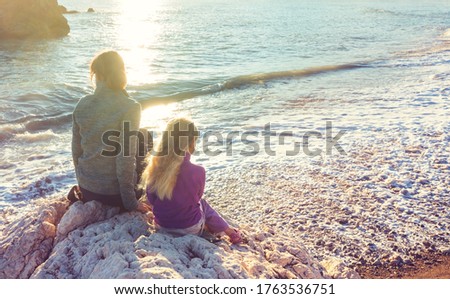Family on the beach on sunset. Mother and daughter running together.