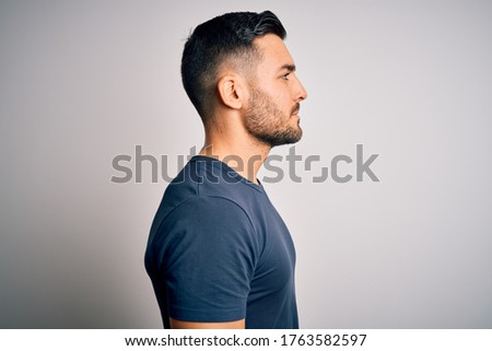 Young handsome man wearing casual t-shirt standing over isolated white background looking to side, relax profile pose with natural face with confident smile. Royalty-Free Stock Photo #1763582597