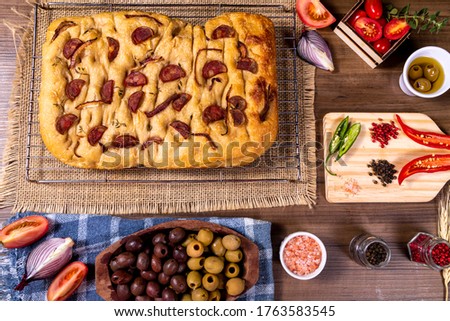 Traditional Italian Focaccia with pepperoni, cherry tomatoes, black olives, rosemary ando onion - homemade flat bread focaccia