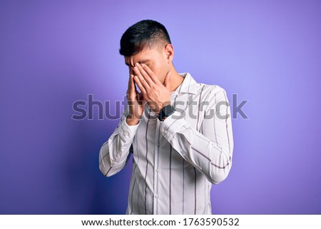 Young handsome hispanic man wearing elegant business shirt standing over purple background rubbing eyes for fatigue and headache, sleepy and tired expression. Vision problem