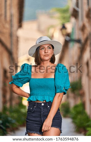 Pretty young woman in blue top walking down the street in Valldemossa old city. Travel and wanderlust concept.