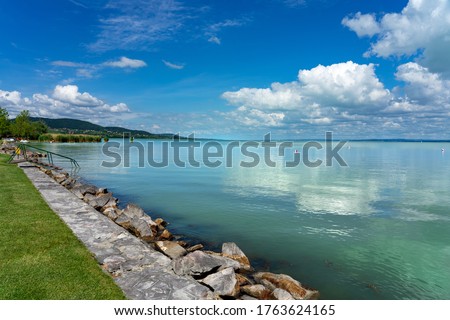 simple picture about Lake Balaton in Hungary from Badacsony beach with blue sky and cloud refletion and stairs into the water