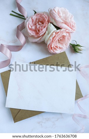 card for invitation or congratulation with flowers. a small bouquet of pink roses and an envelope on a white background. wedding invitation.