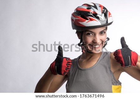 Woman cyclist with technical helmet and gray tank top makes the ok sign with the thumb up isolated on a light background