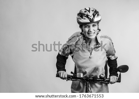 Black and white photo of woman cyclist struggling uphill on bicycle isolated on light background