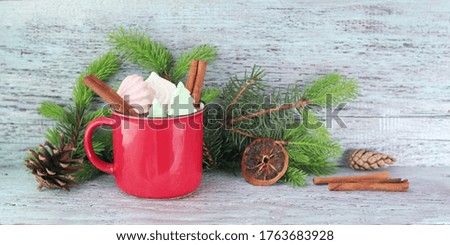 Merry Christmas, red cup with chocolate, meringues and spices, spruce branches, cones on a wooden background, congratulations on winter seasonal holidays, banner