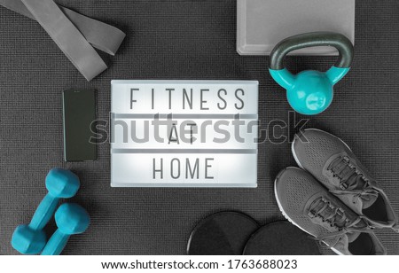 Fitness at home strength training program with dumbbells weights, resistance bands for cross fit workout on exercise mat .Top view of lightbox sign with black grey equipment.