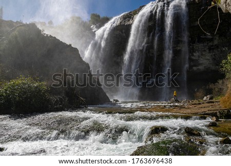 Adventure man looking at Tortum Waterfall in Turkey. Tourist in a yellow jacket relaxing at the Tortum waterfall in Turkey. Landscape view of Tortum Waterfall in Erzurum,Turkey Royalty-Free Stock Photo #1763696438