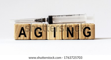 Text AGING made from wooden cubes. White background