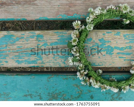 Clover wreath with white flowers, on a turquoise wooden background                               