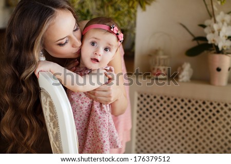 closeup portrait of Mother kissing her angelic baby girl in home interior 