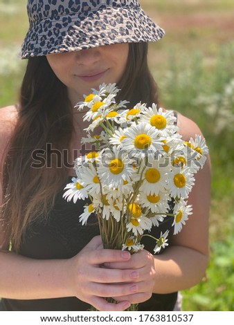 Young beautiful 17 years old girl in cheetah print hat, holding white flowers, happy summer