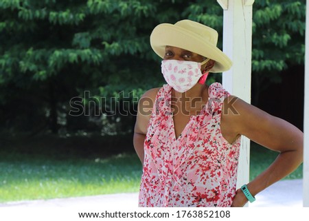 Woman in front of a green backdrop with protective mask on watching what's going on