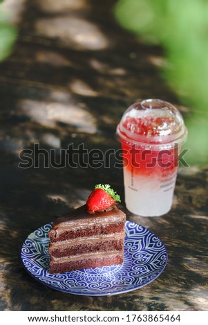 Fresh strawberry syrup and ice cube with soda for summer time with chocolate cake on wooden table background and strawberry fruits with copy space.