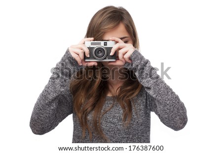 Young woman holding a camera on white background