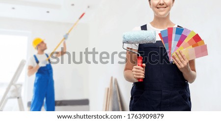 repair, construction and building concept - close up of happy smiling female painter or builder with paint roller and color charts over man painting ceiling background