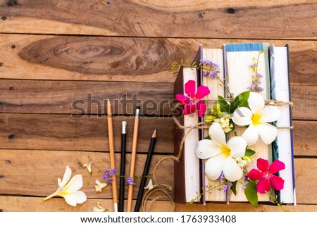 dictionary book, diary  bundle by rope and flowers frangipani ,jasmine ,purple flowers arrangement flat lay style on background wooden