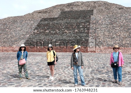 A group of Asian female tourist posing for a picture in front of the Pyramid of the Moon in Teotihuacán Municipality.
