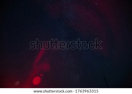 Photo of nightly blue sky with stars and red light