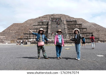 A group of Asian female tourist posing for a picture in front of the Pyramid of the Moon in Teotihuacán Municipality.