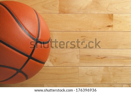 A basketball on a wood gym floor viewed from above