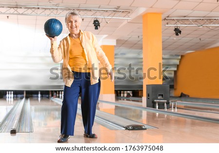 Senior woman playing bowling in club