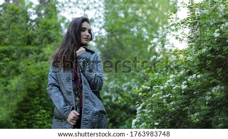 Summer portrait of a beautiful luxurious woman with brown hair on a background of a blooming garden