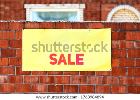 The inscription on the banner "sale" on the brick fence