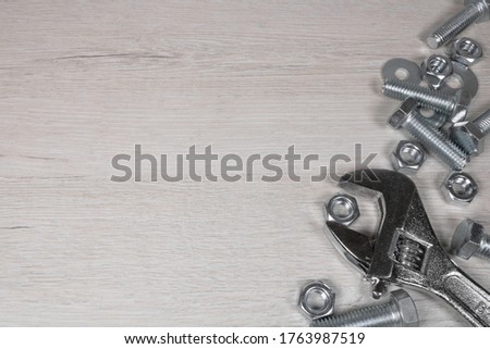 Background with metal bolts and a steel adjustable wrench. Background on the theme of engineering or construction.