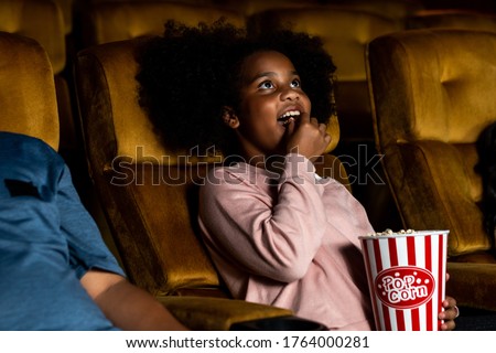 Three children having fun and enjoy watching movie in cinema Royalty-Free Stock Photo #1764000281