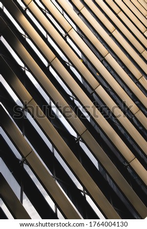 Close up image of an abstract and repetitive brown steel texture and pattern on the glass facade of a modern business building