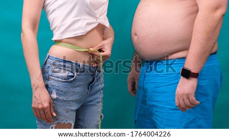 Couple Fat man and thin woman standing together, wrapped in tape measure. Diet, family weight loss and healthcare concept
