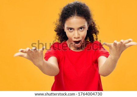 A woman in a red T-shirt looks at the camera or gestures with her hands
