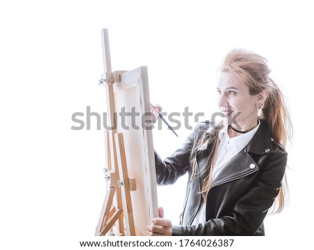 A beautiful woman artist draws on a easel on a bright white background. Style is a high key.