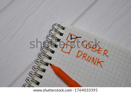 Sober and Drunk write on a book. Supported by an additional services isolated wooden table.