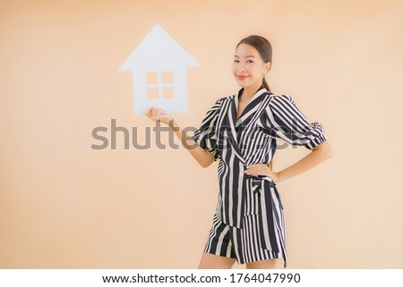 Portrait beautiful young asian woman show home or house paper sign on brown background