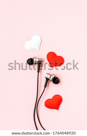 Red heart with music earphones on pink pastel background. Headphones are like a pair of lovers. Romantic and love. Valentines Day backdrop. Minimalist postcard.