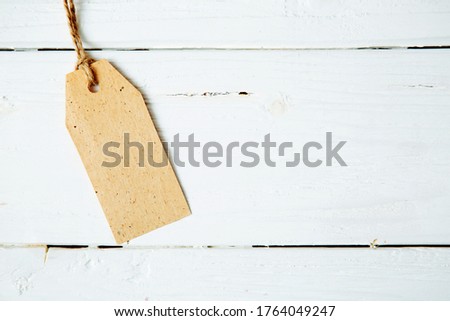 Label tag blank on wooden One paper blank tags with rope on wooden background.