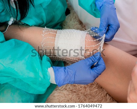 home doctor puts a bandage on the patient's knee with an elastic tubular mesh. Royalty-Free Stock Photo #1764049472