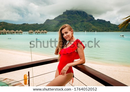 beautiful girl posing in red swimsuit on the beach