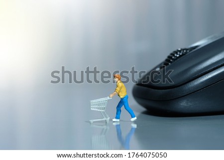 Online shopping. Women with cart in front of black mouse. Miniature people figurines toys conceptual photography.