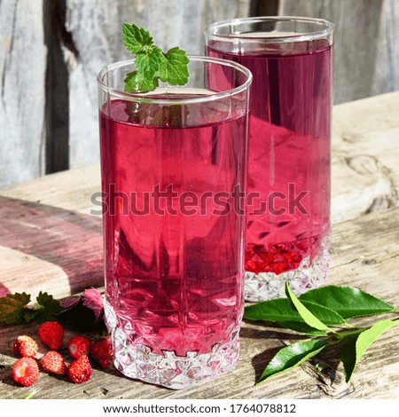 Fresh summer cherry cocktail. Glass of strawberry soda drink on wooden background.